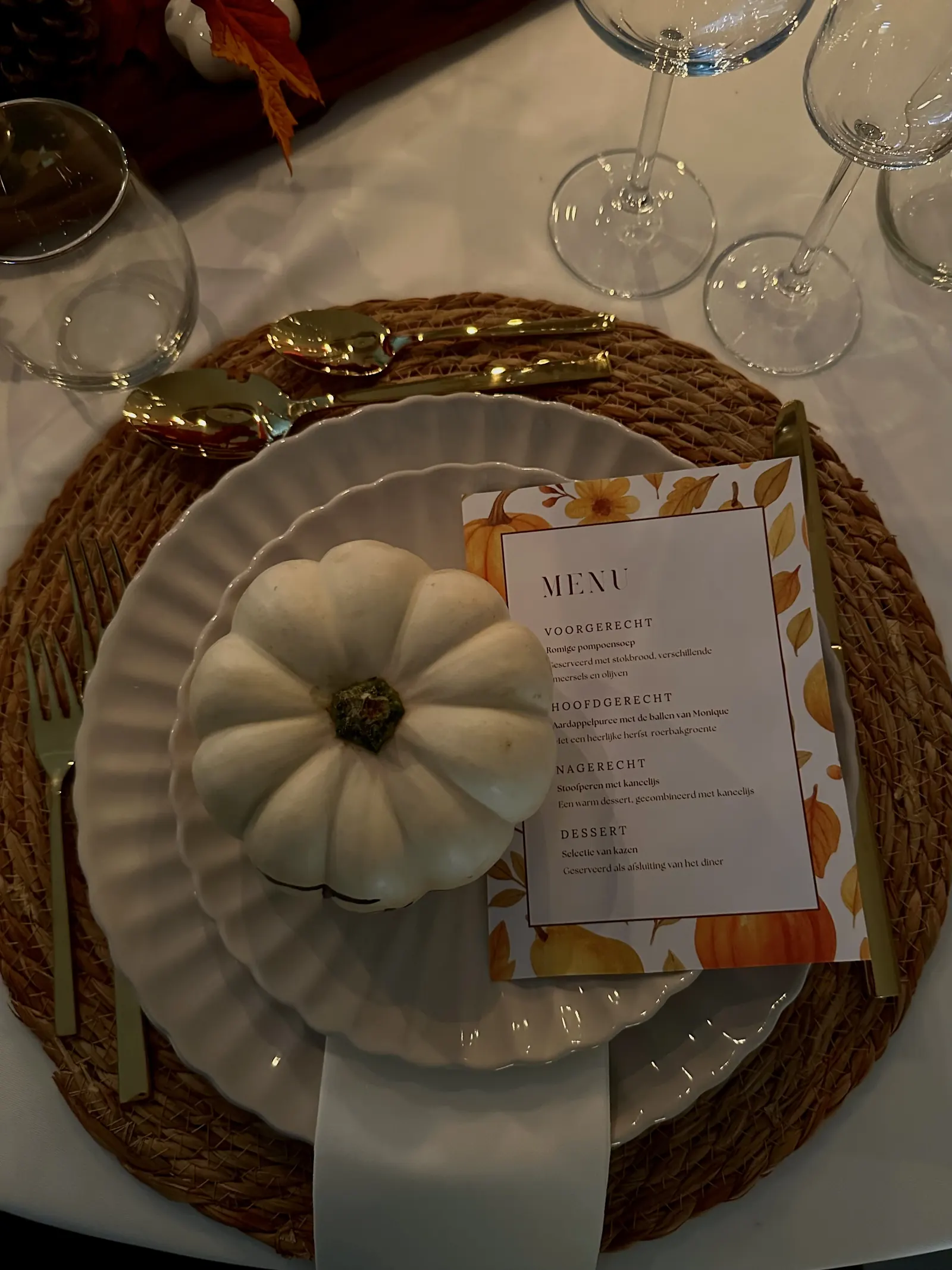 Bord met een witte minipompoen en een menukaart in herfsttinten op een rieten placemat