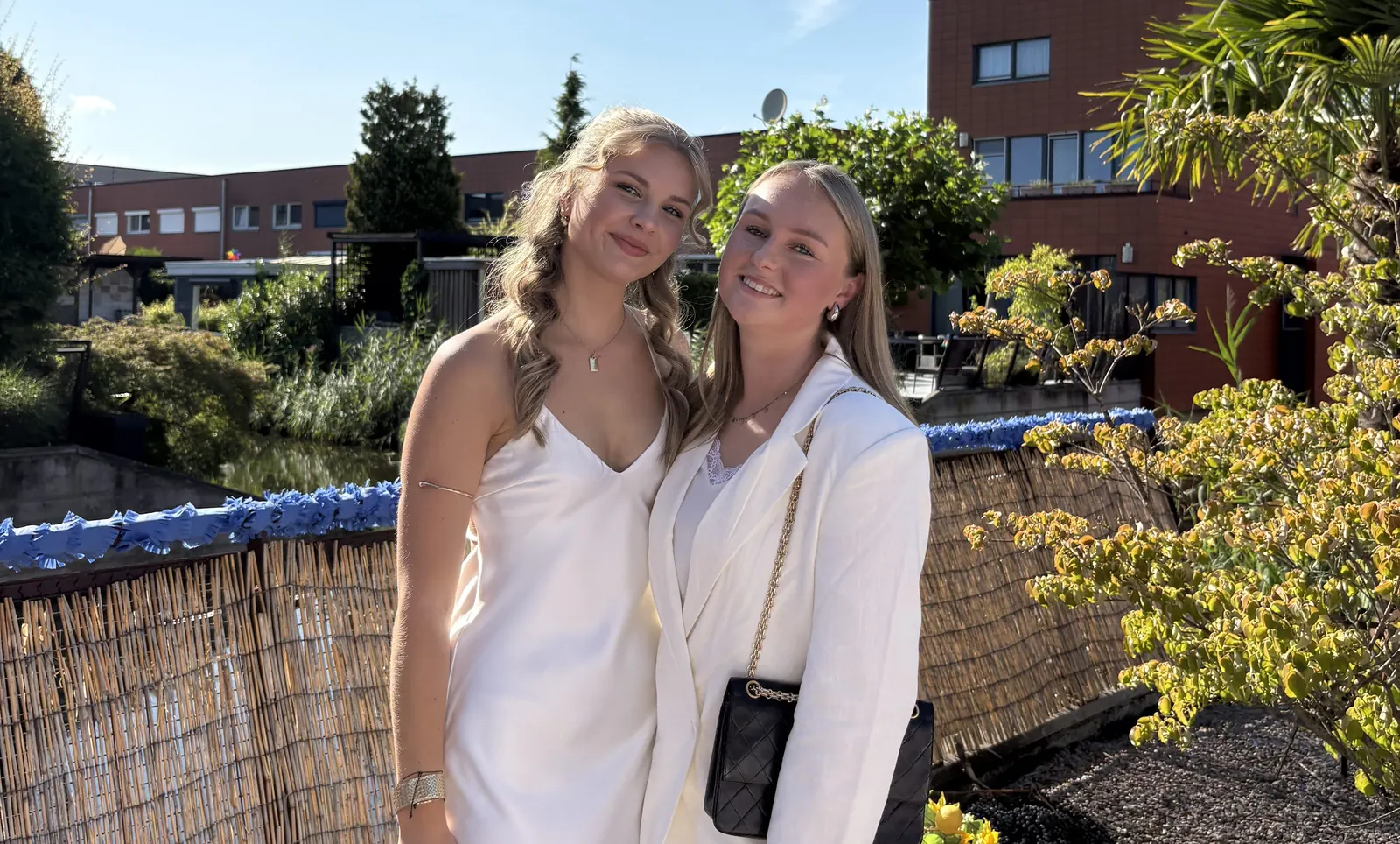 Charlize en Sanne, allebei in het wit, buiten op een zomerse dag