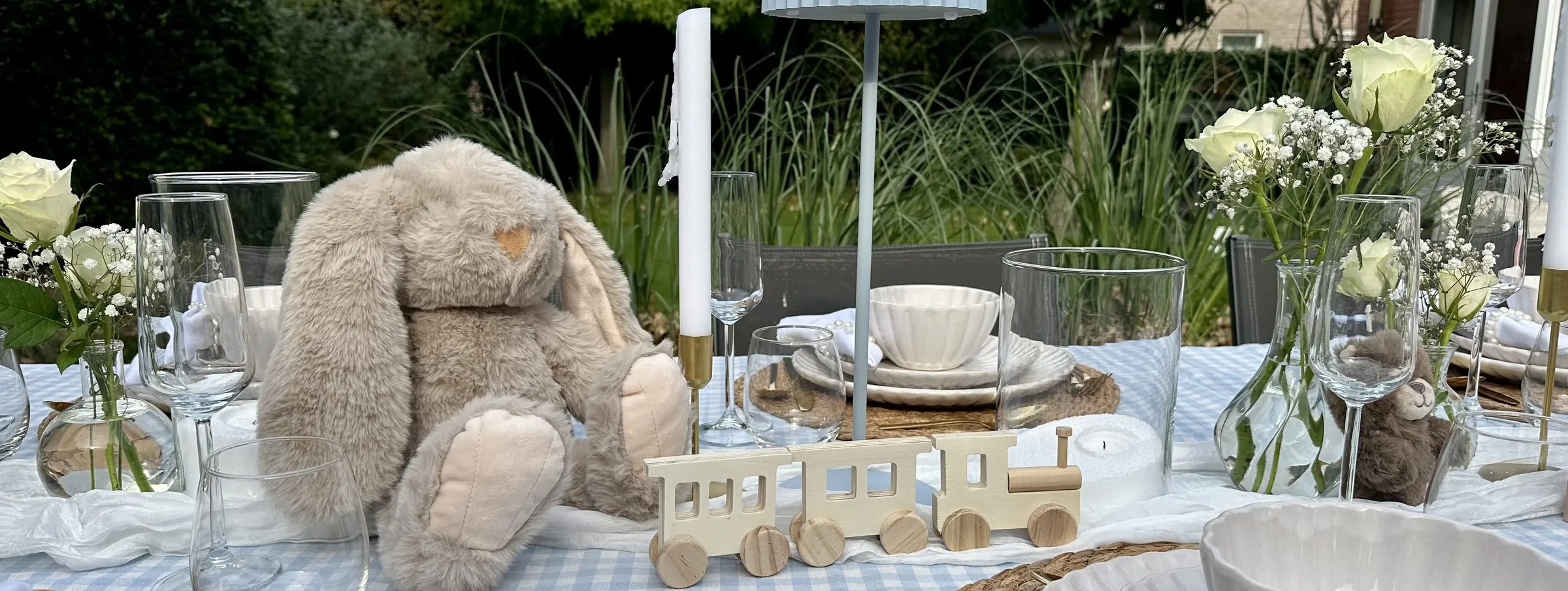Babyshowertafel met een knuffelkonijn, een houten trein en witte bloemen