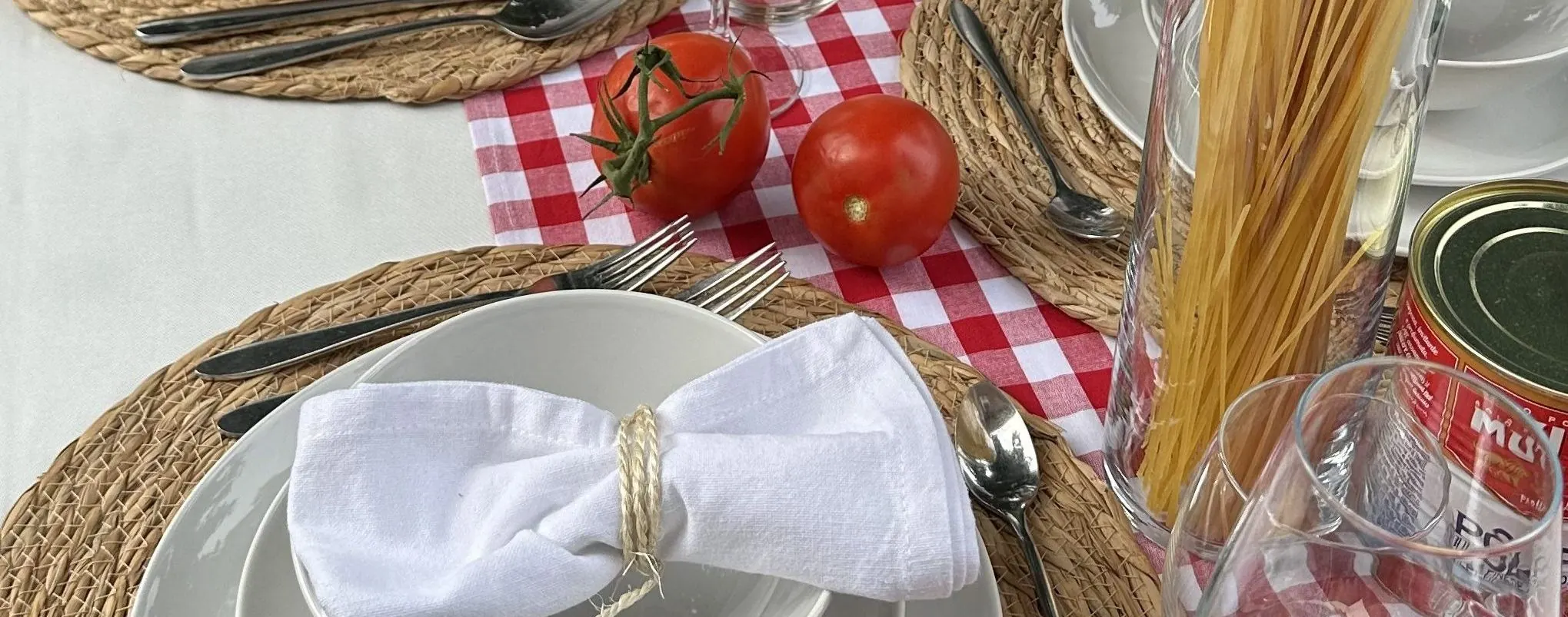 Italiaans gedekte tafel met tomaten, spaghetti en een wit servet met touw