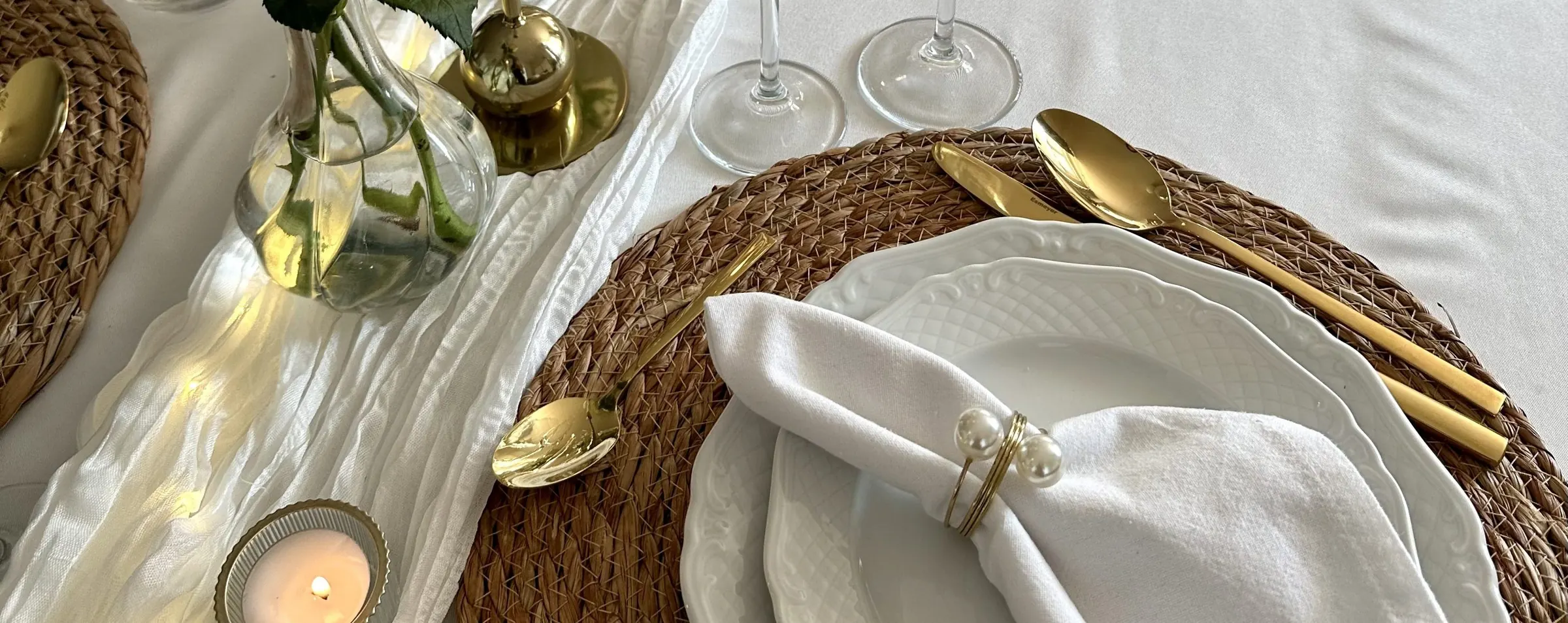 Gedekte tafel met wit servies, een servet met gouden servetring en waxinelichtjes
