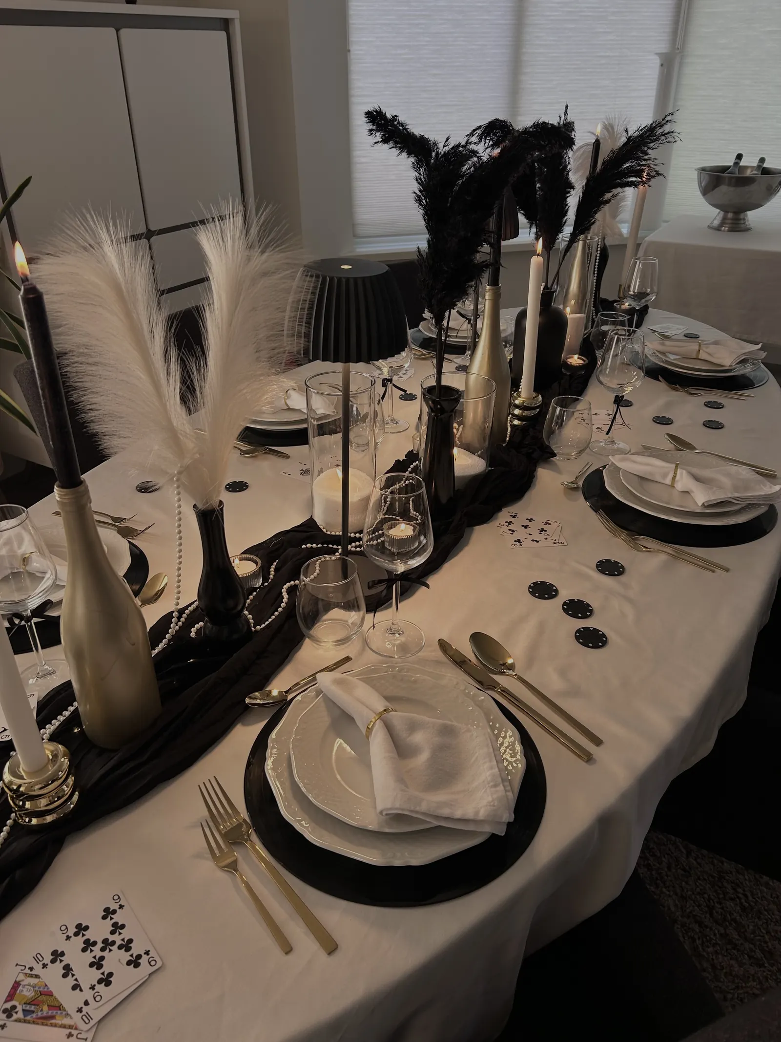 Lange Casino Royale tafel met zwarte en witte pluimen, gouden flessen en zwarte onderborden