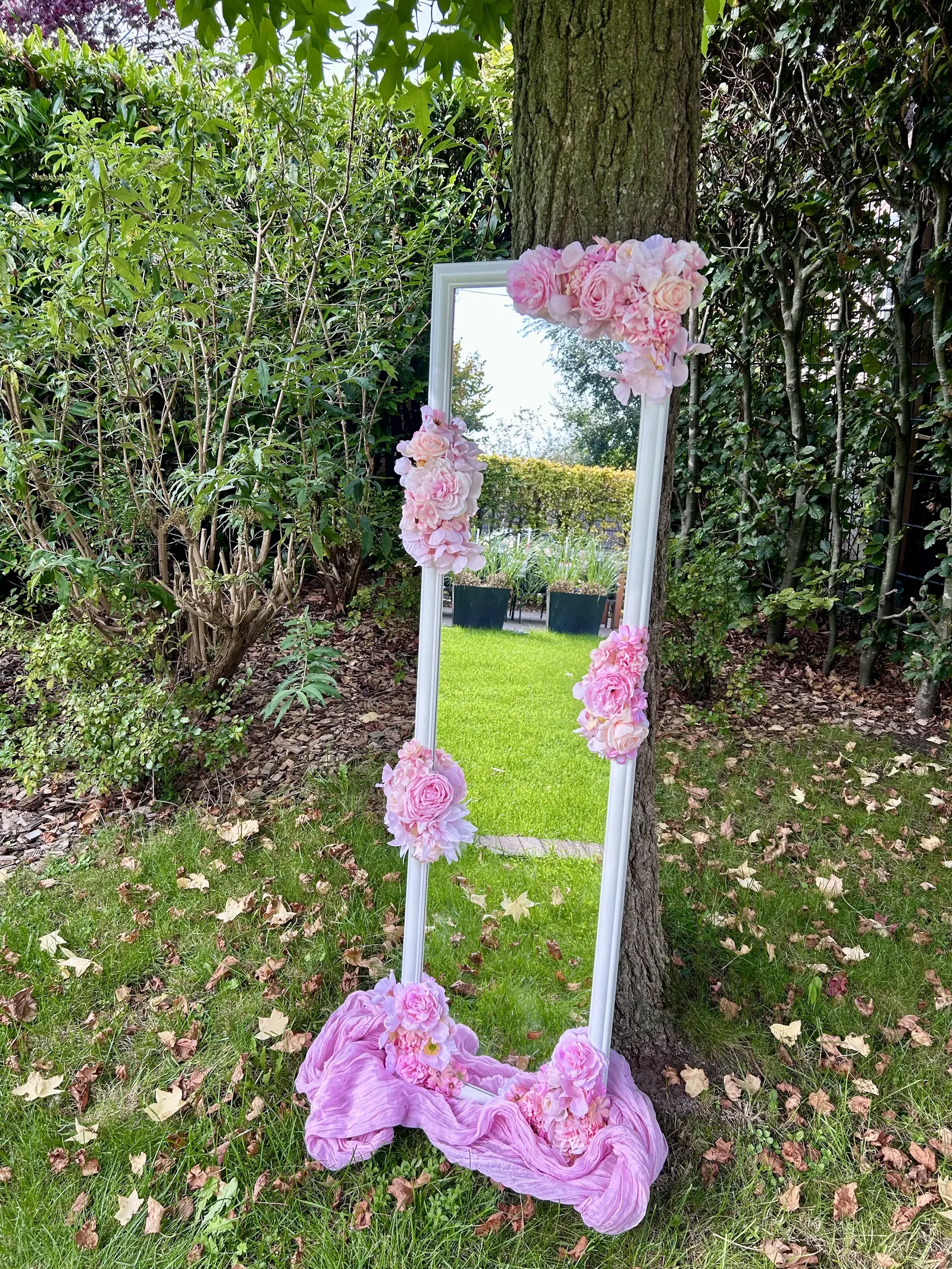 Staande witte spiegel met roze bloemen in de tuin