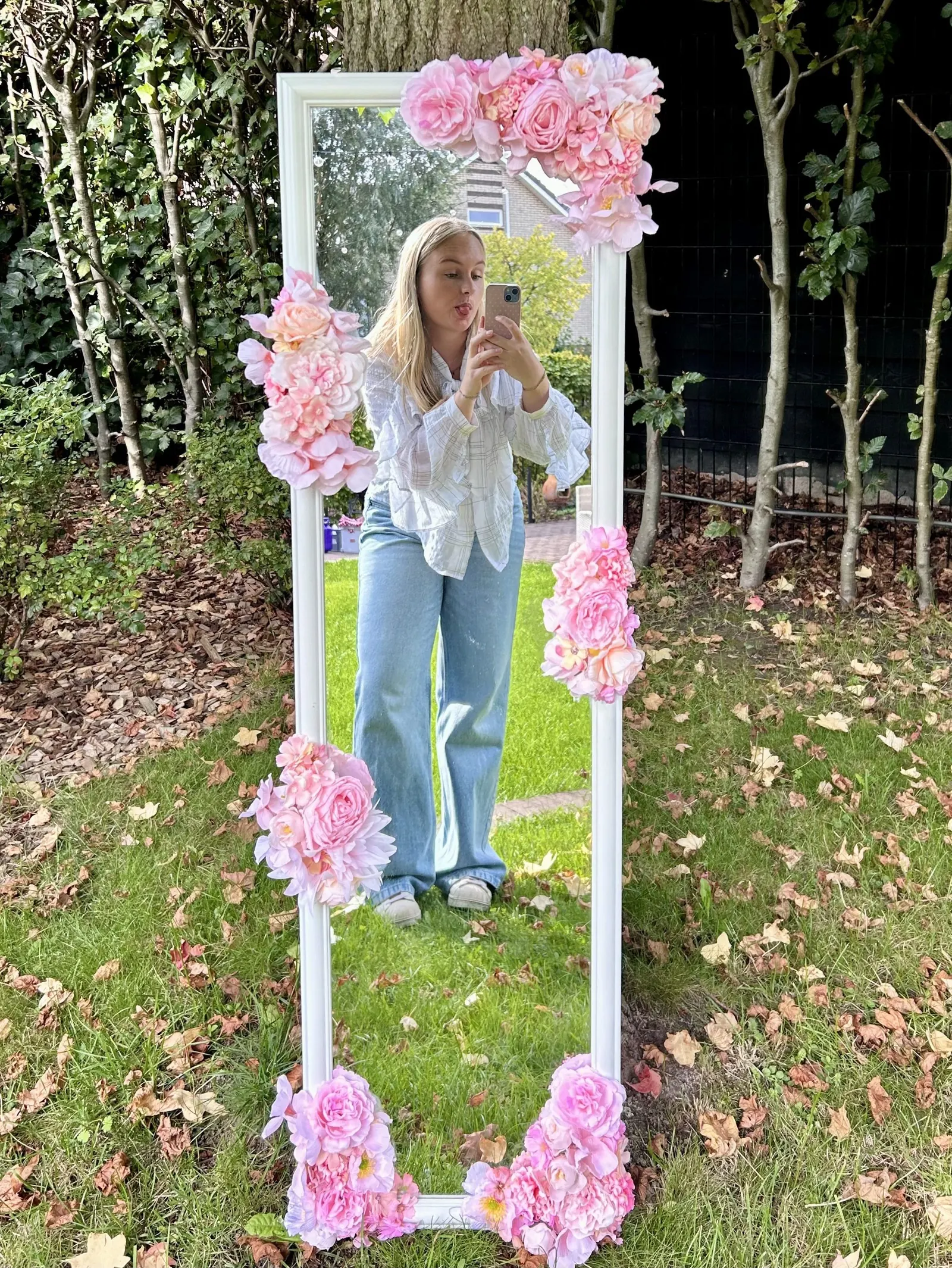 Iemand maakt een foto in de witte spiegel met roze bloemen