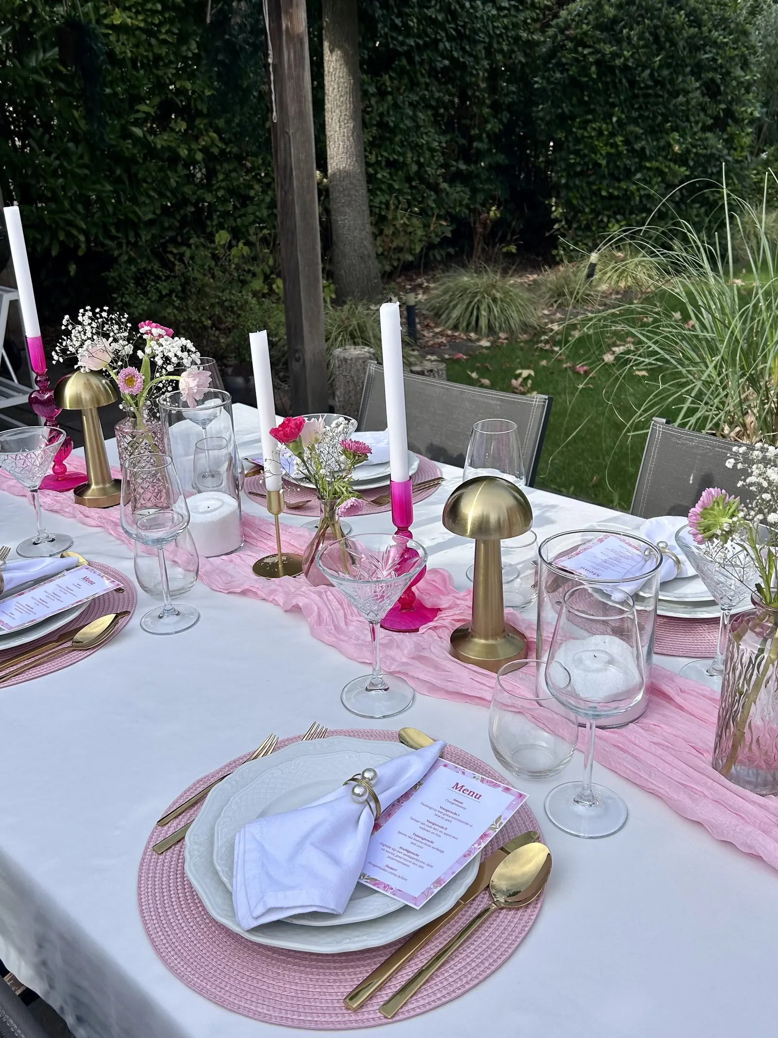La Vie en Rosé tafel buiten in de tuin met roze loper, gouden lampjes en roze kandelaars