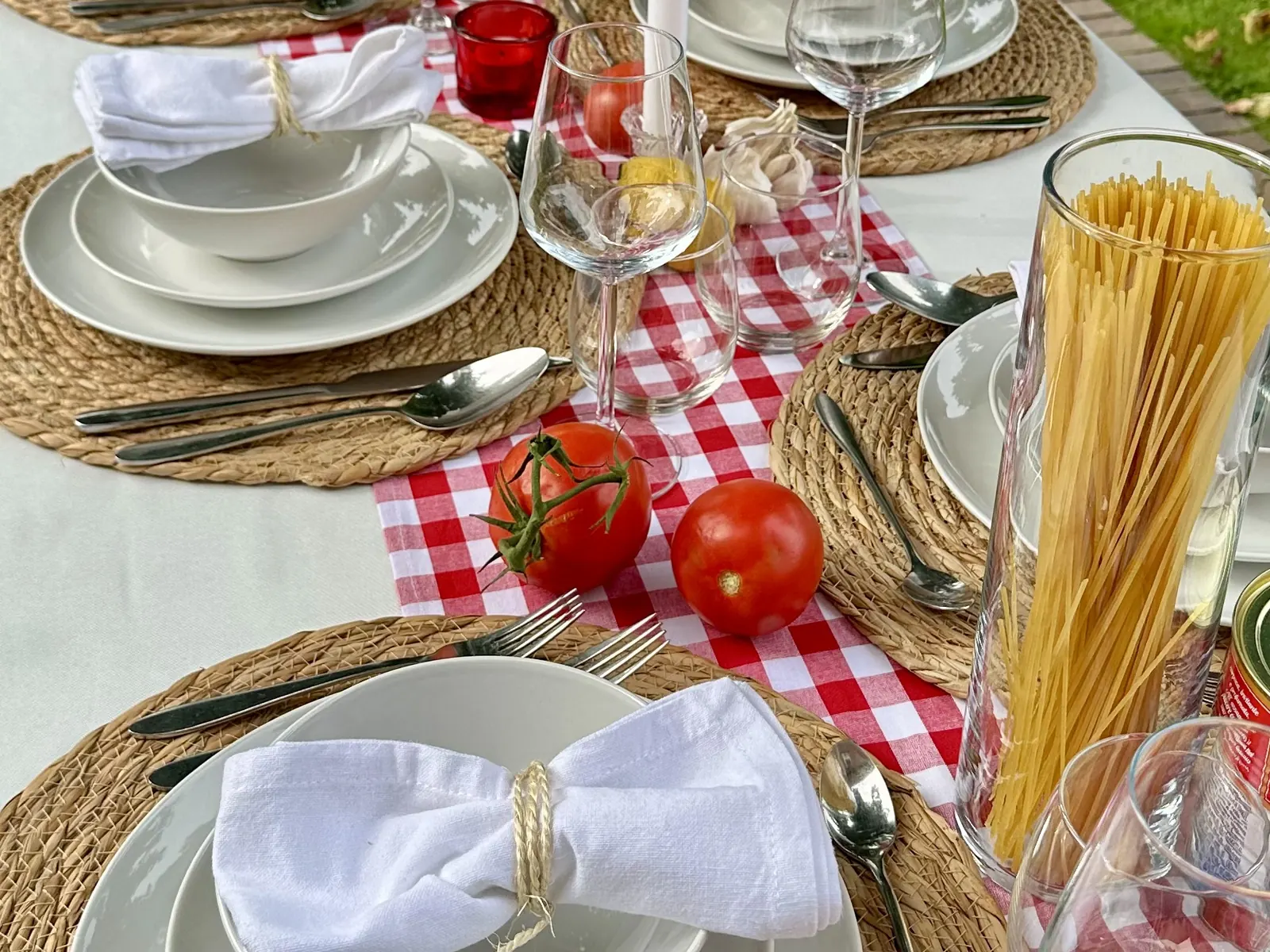 Detail van de Italian Nights tafel met tomaten, spaghetti en een rood-wit geblokte loper