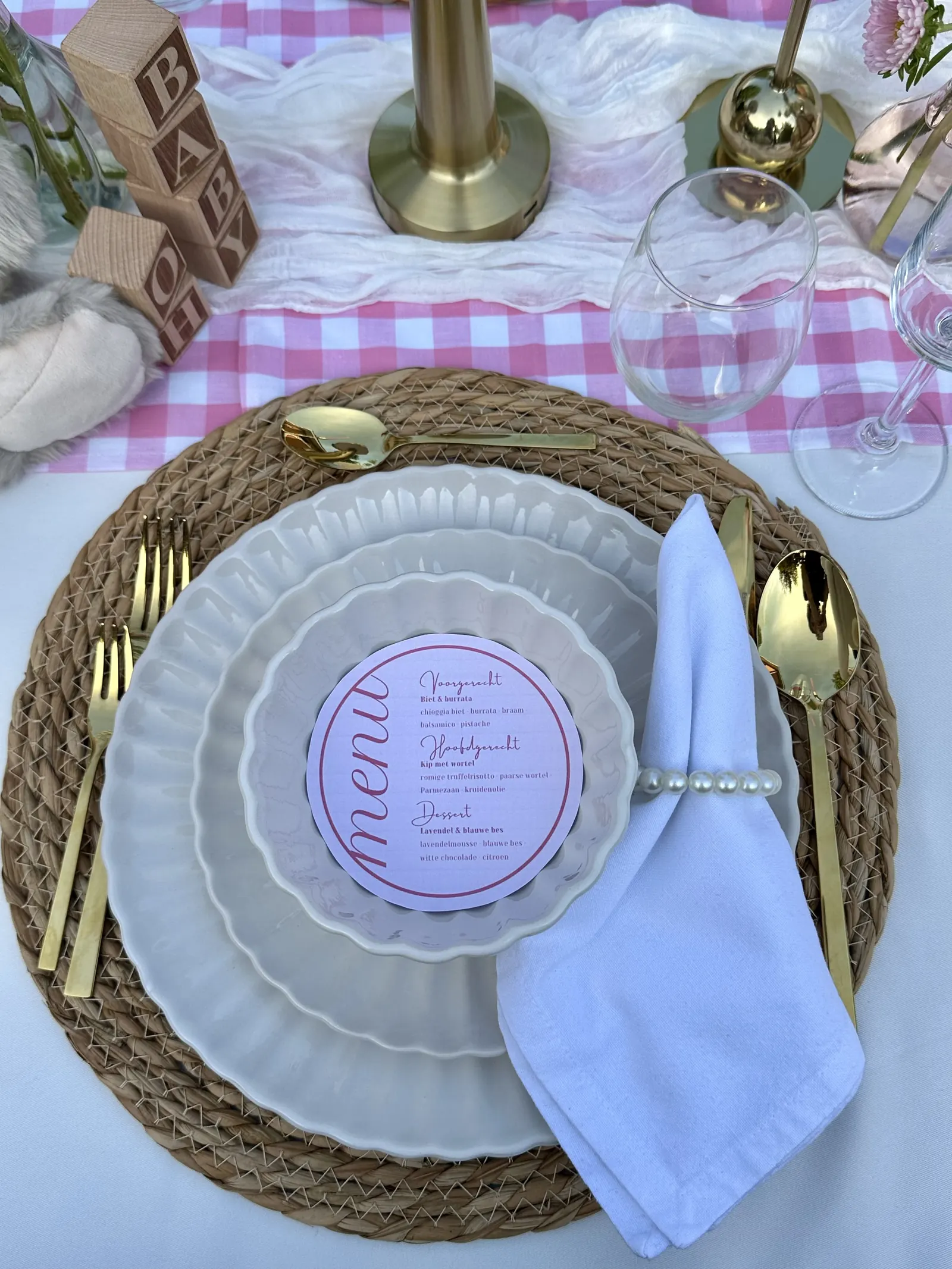 Ronde roze menukaart op een bord met parelservetring en gouden bestek