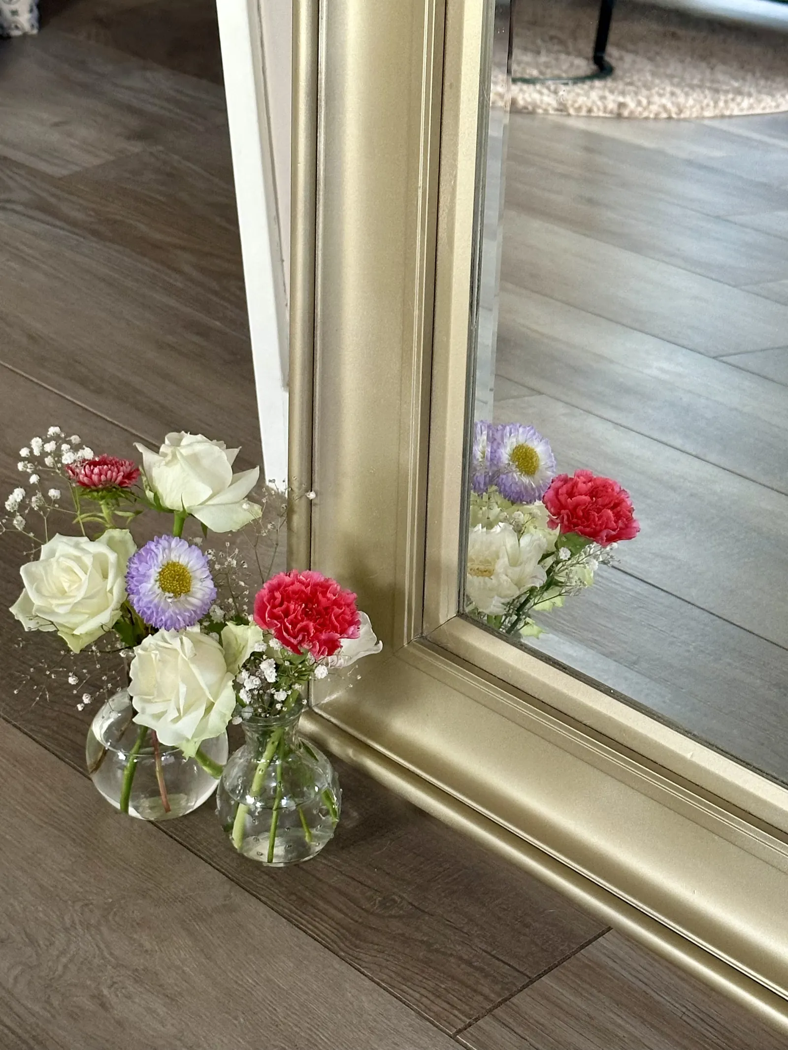Detail van de gouden spiegellijst met witte rozen en gekleurde bloemen in vaasjes