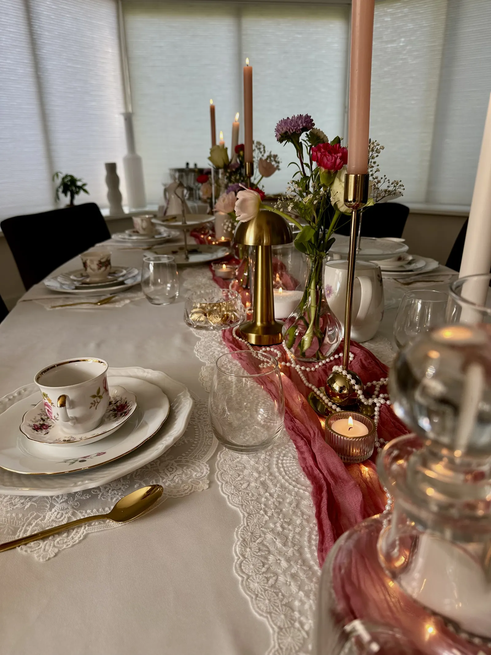 Afternoon Tea tafel met theekopjes, een gouden tafellampje en bloemen in vaasjes