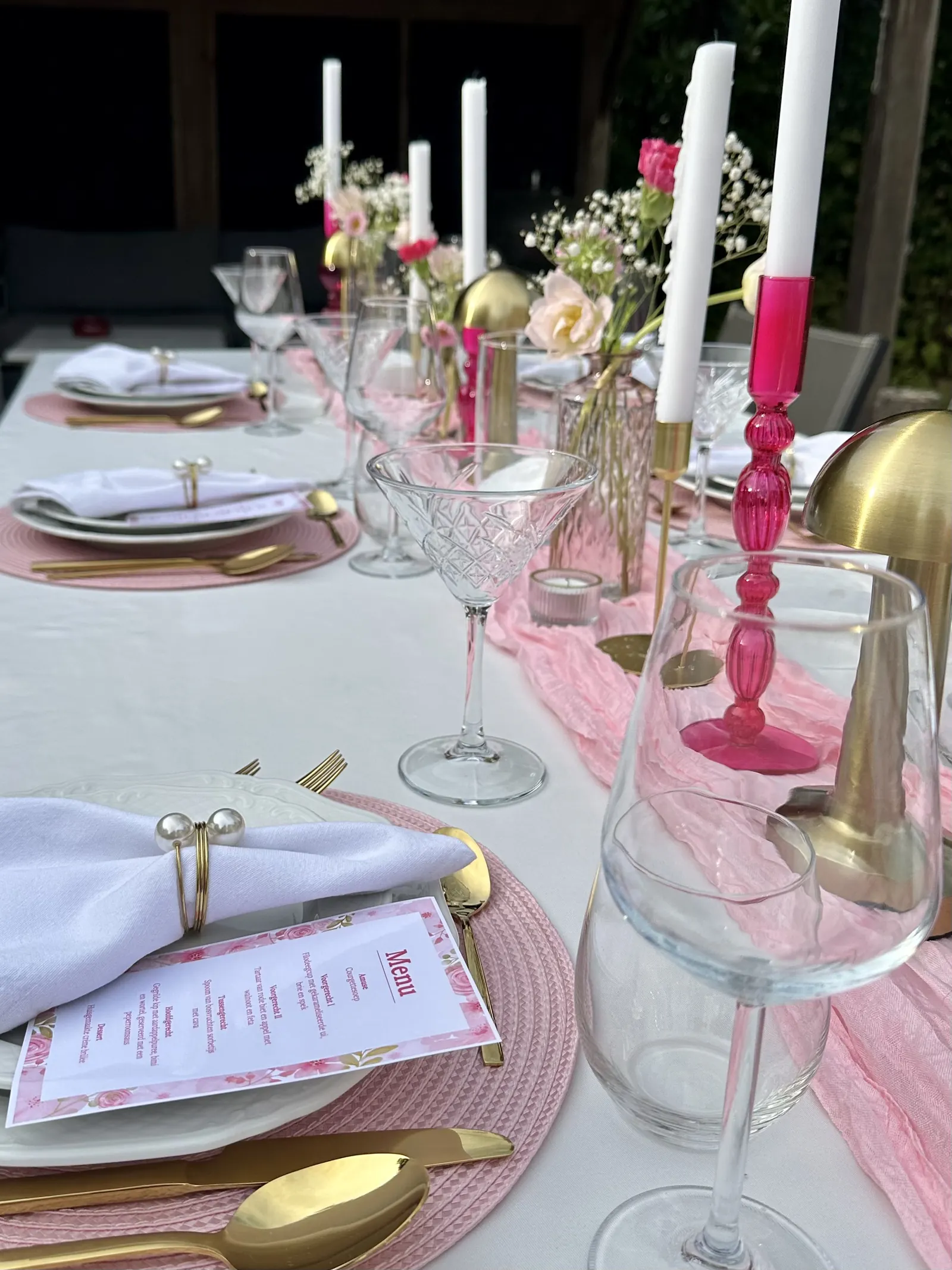 Roze menukaart op het bord, met kristallen glazen en een roze kandelaar