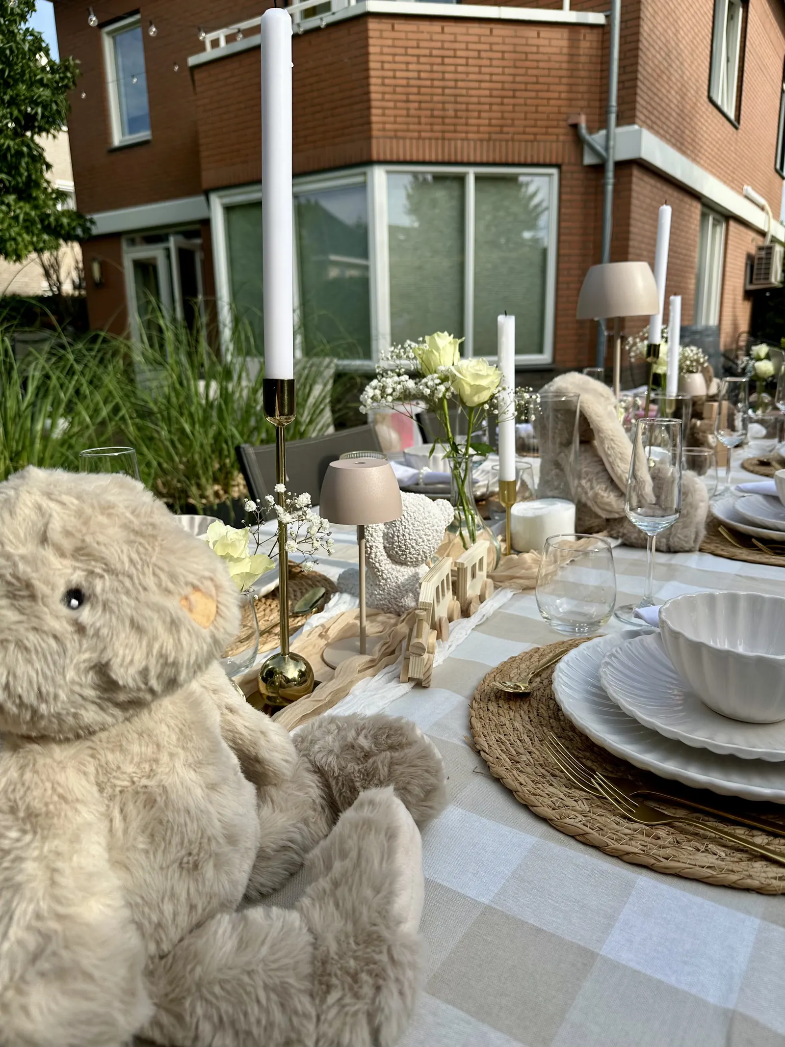 Knuffelbeer aan de beige babyshowertafel met witte schaaltjes en kaarsen