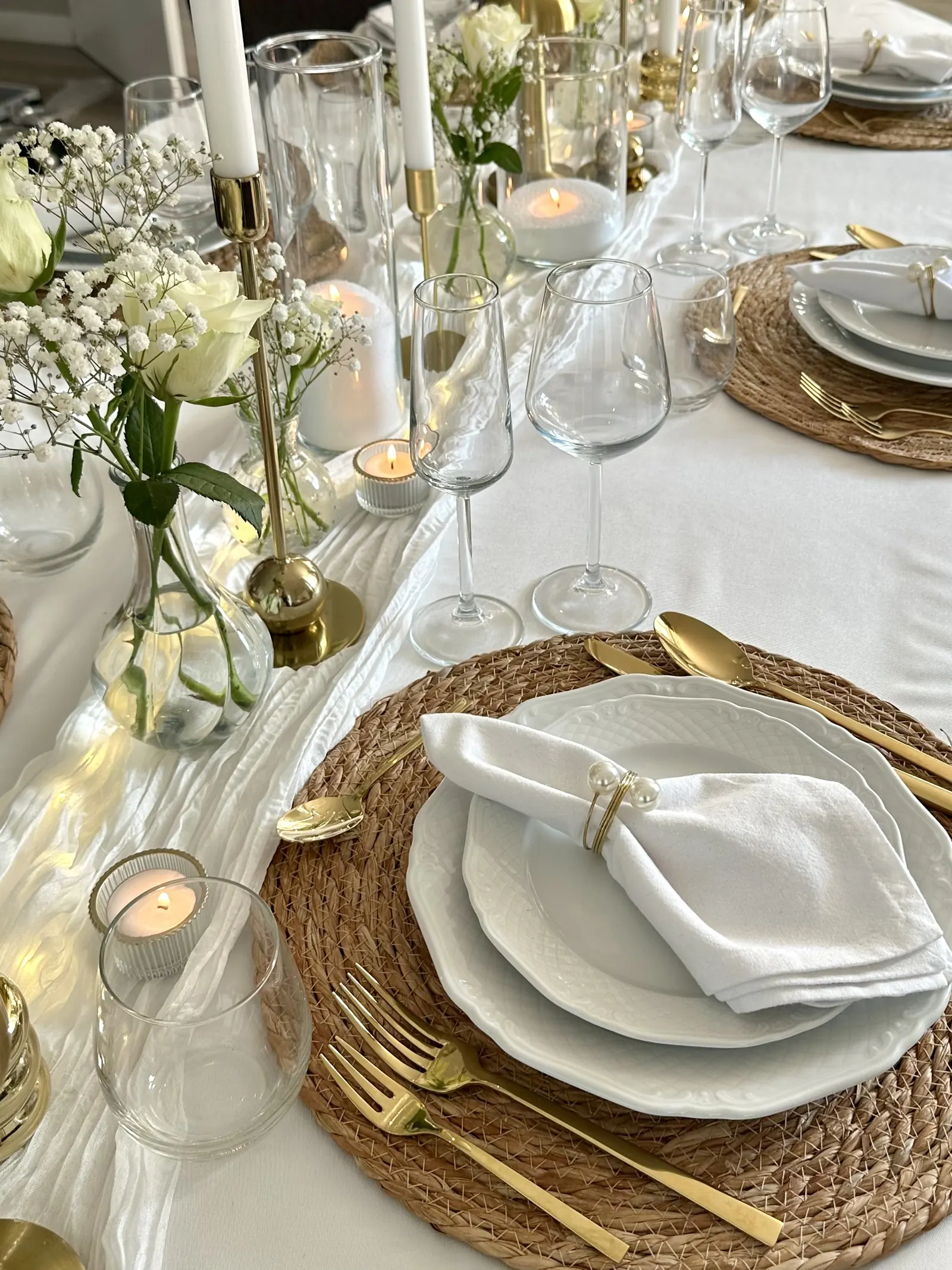 Witte rozen, gipskruid en waxinelichtjes langs een witte loper met gouden kandelaars