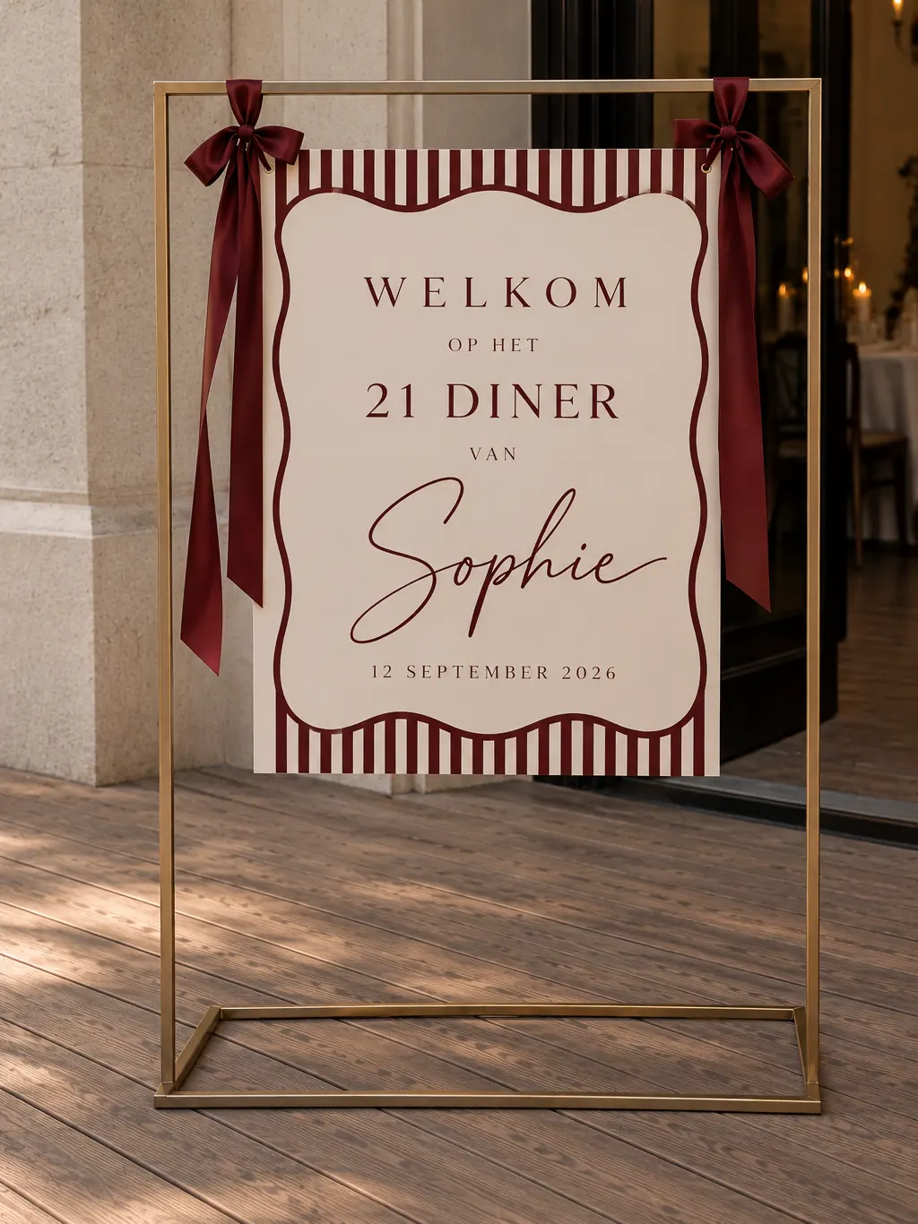 Gestreept welkomstbord met de naam Sophie in een gouden standaard met strikken